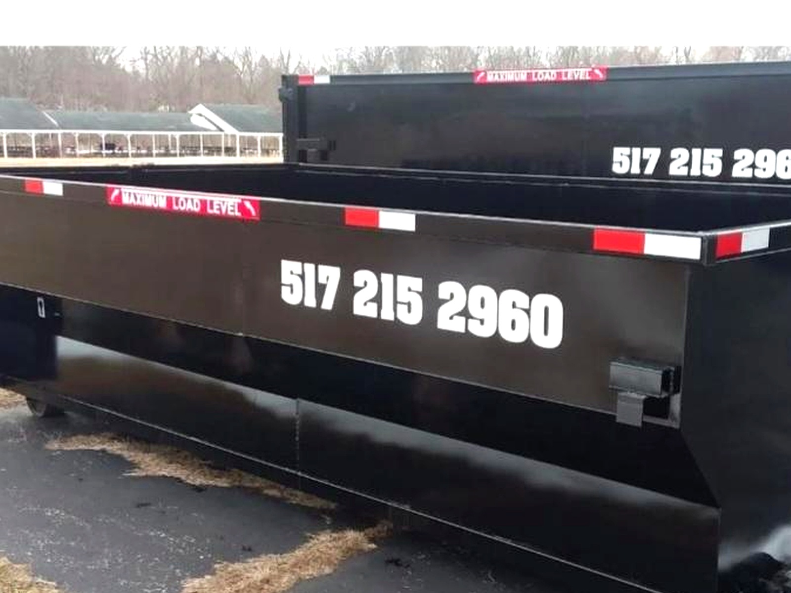 21 Yard Dumpster — black Skeels dumpster with 517 215 2960 on the side