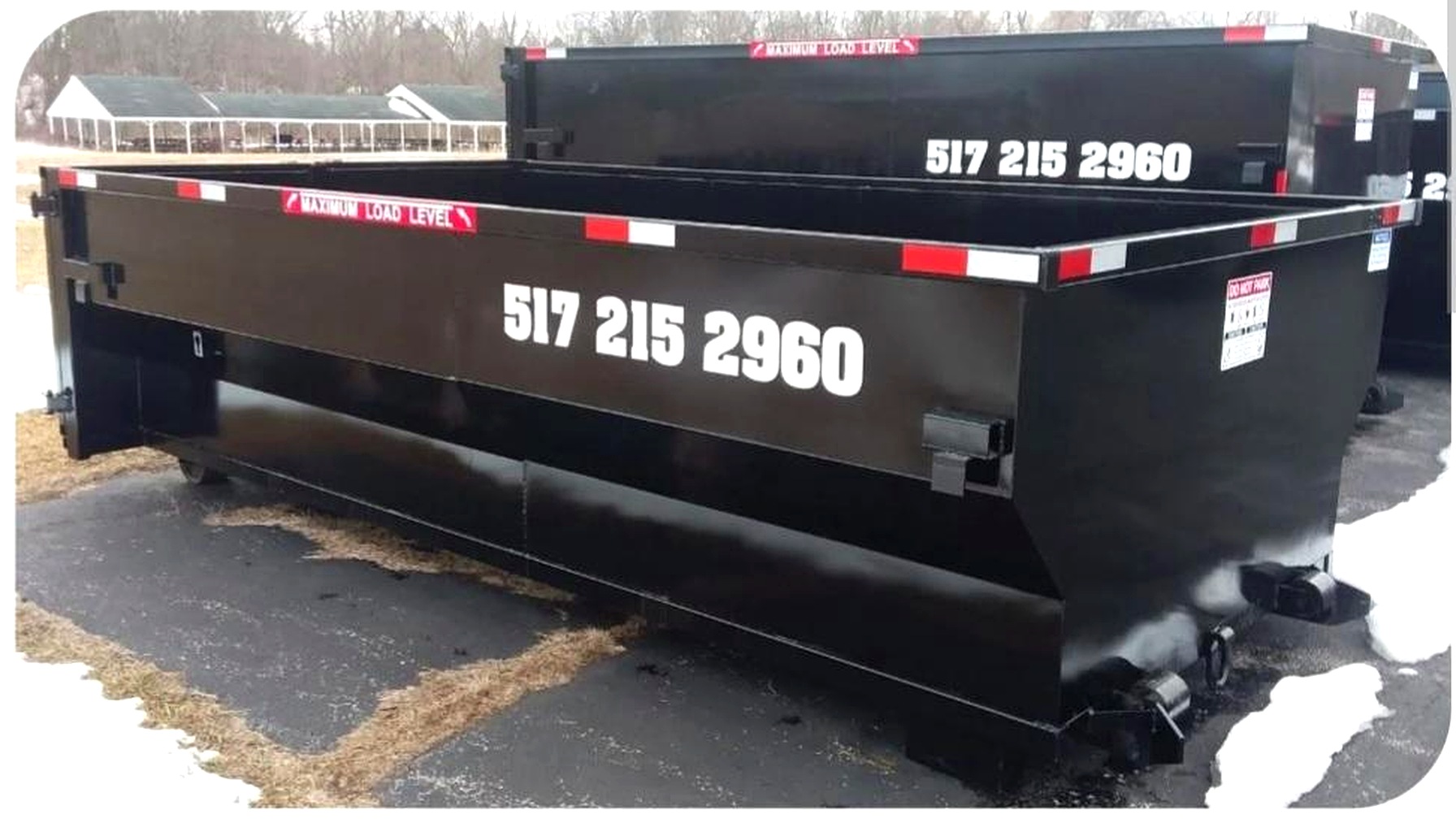 Black Skeels dumpster with 517 215 2960 on the side, parked on the lot